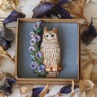 Owl brooch pin. Ceramic eagle owl sits on a branch with blue flowers. Pottery brooch eagle-owl.